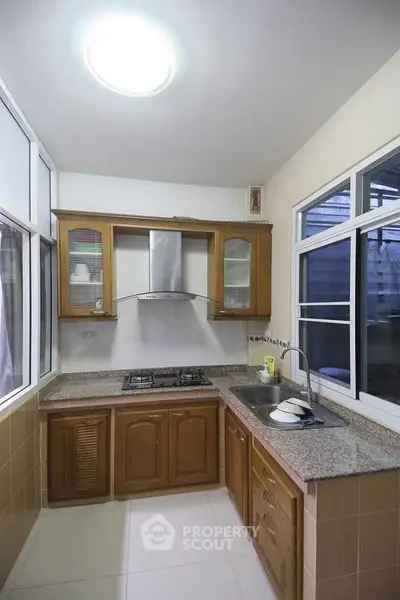 Charming kitchen with closed layout and gas stove, featuring wooden cabinets and modern fixtures.