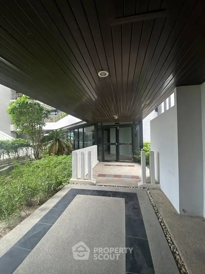 Modern building entrance with sleek design and lush greenery