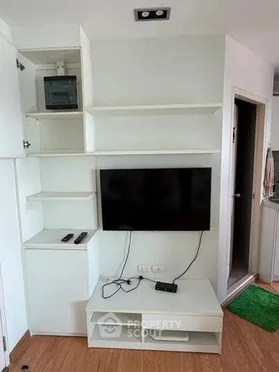 Modern living room with built-in shelves and flat-screen TV, showcasing sleek design and functionality.