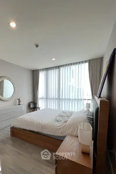 Spacious bedroom with modern decor and large window offering natural light.
