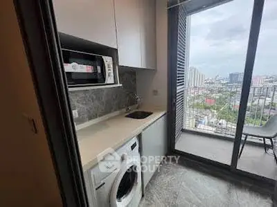 Modern kitchen with appliances and balcony view in high-rise apartment