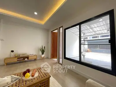 Modern living room with large window and stylish decor, showcasing open space and natural light.