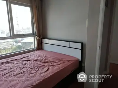 Spacious bedroom with large window offering ample natural light and a view of the city, perfect for relaxation and comfort in a modern urban home.