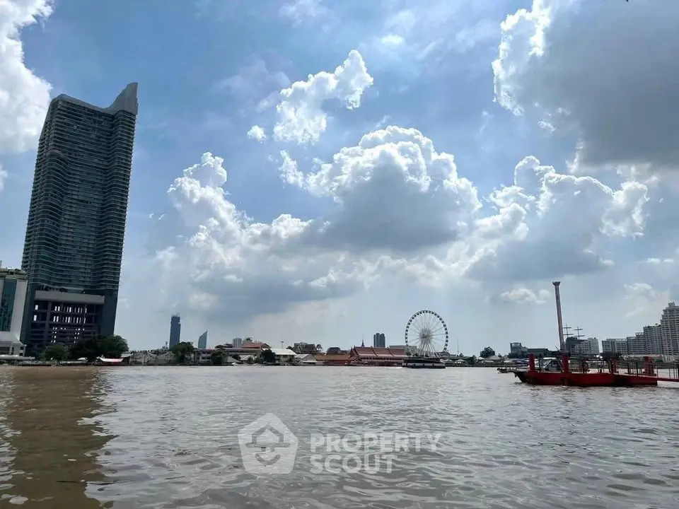 Stunning riverside view with modern skyscraper and Ferris wheel under a vibrant sky.