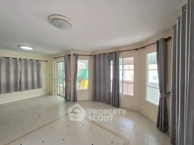 Spacious corner unit living room with large windows and tiled flooring.