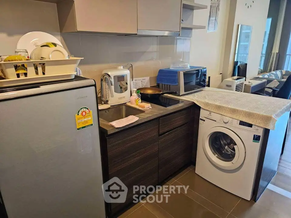 Modern kitchen with appliances including fridge, washing machine, and microwave in compact layout.