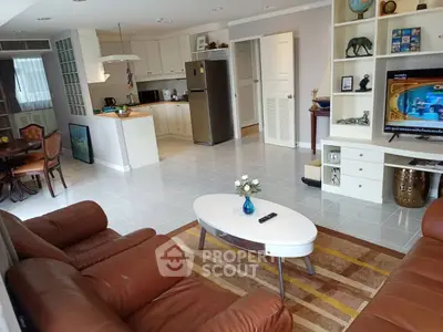Spacious living room with leather sofas and modern kitchen in open layout apartment.