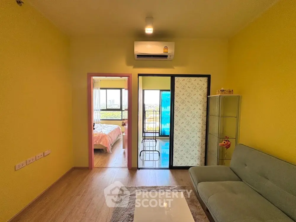 Bright living room with modern sofa and view into cozy bedroom