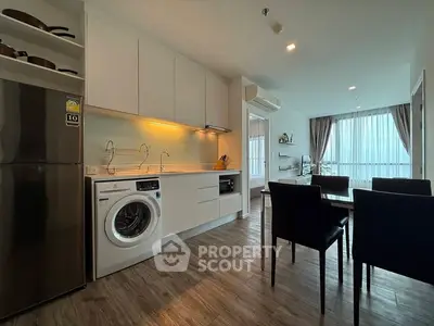 Modern kitchen and dining area with washing machine and sleek appliances in open layout.