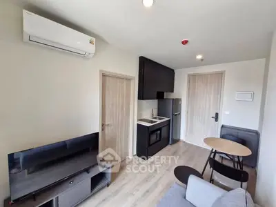 Modern compact living room with kitchenette, featuring sleek appliances and stylish furniture.