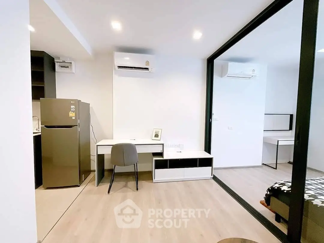 Modern apartment interior with sleek design and air conditioning, featuring a compact kitchen and stylish workspace.