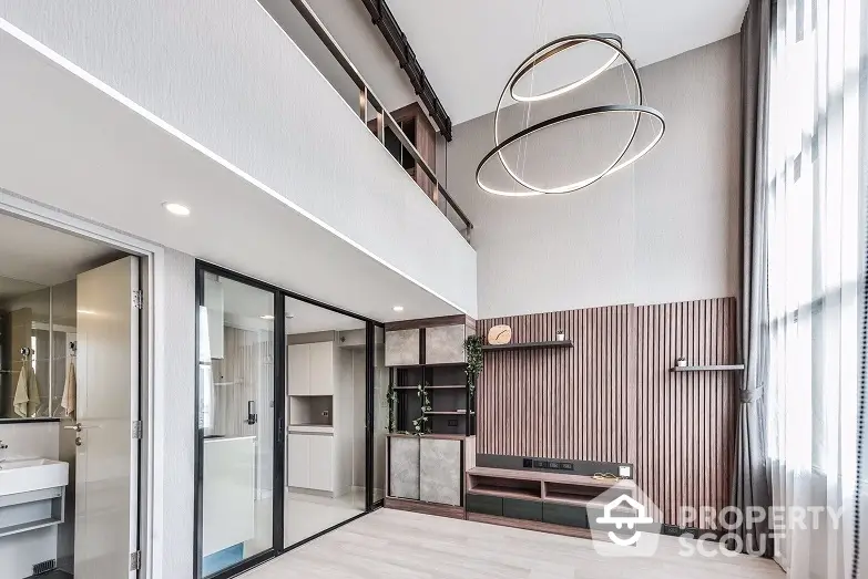 Modern duplex apartment with high ceilings, chic pendant lighting, and sleek wooden accents, featuring an open layout kitchen and a cozy living space.