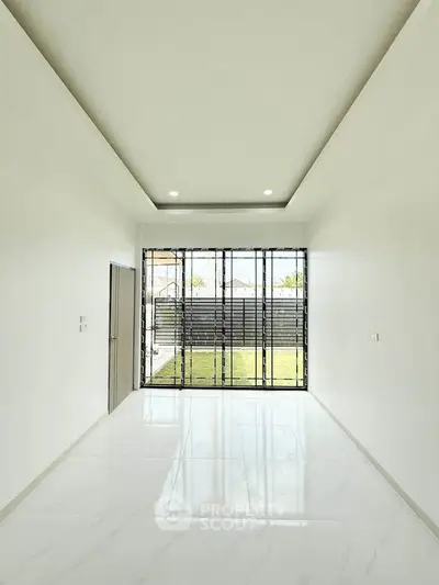 Spacious modern living room with large windows and sleek white flooring, offering abundant natural light.