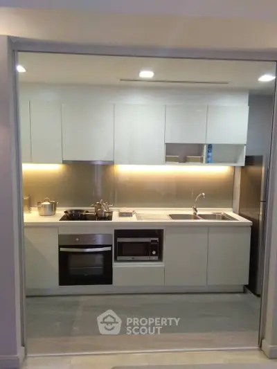 Modern kitchen with sleek cabinetry and built-in appliances, featuring a stylish open layout and elegant lighting.