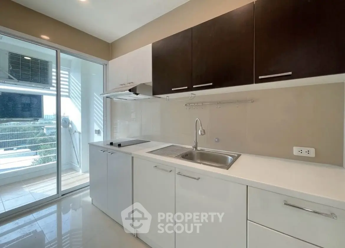 Modern kitchen with sleek cabinetry and balcony view, perfect for urban living.