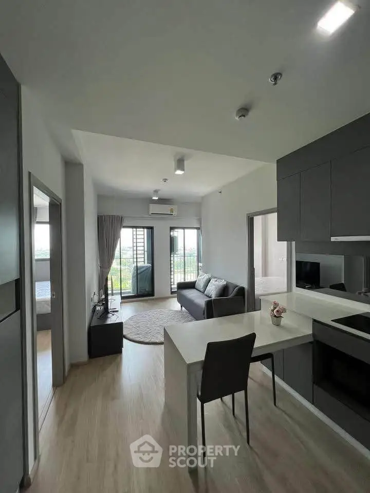 Modern open-plan living room with sleek kitchen and balcony view