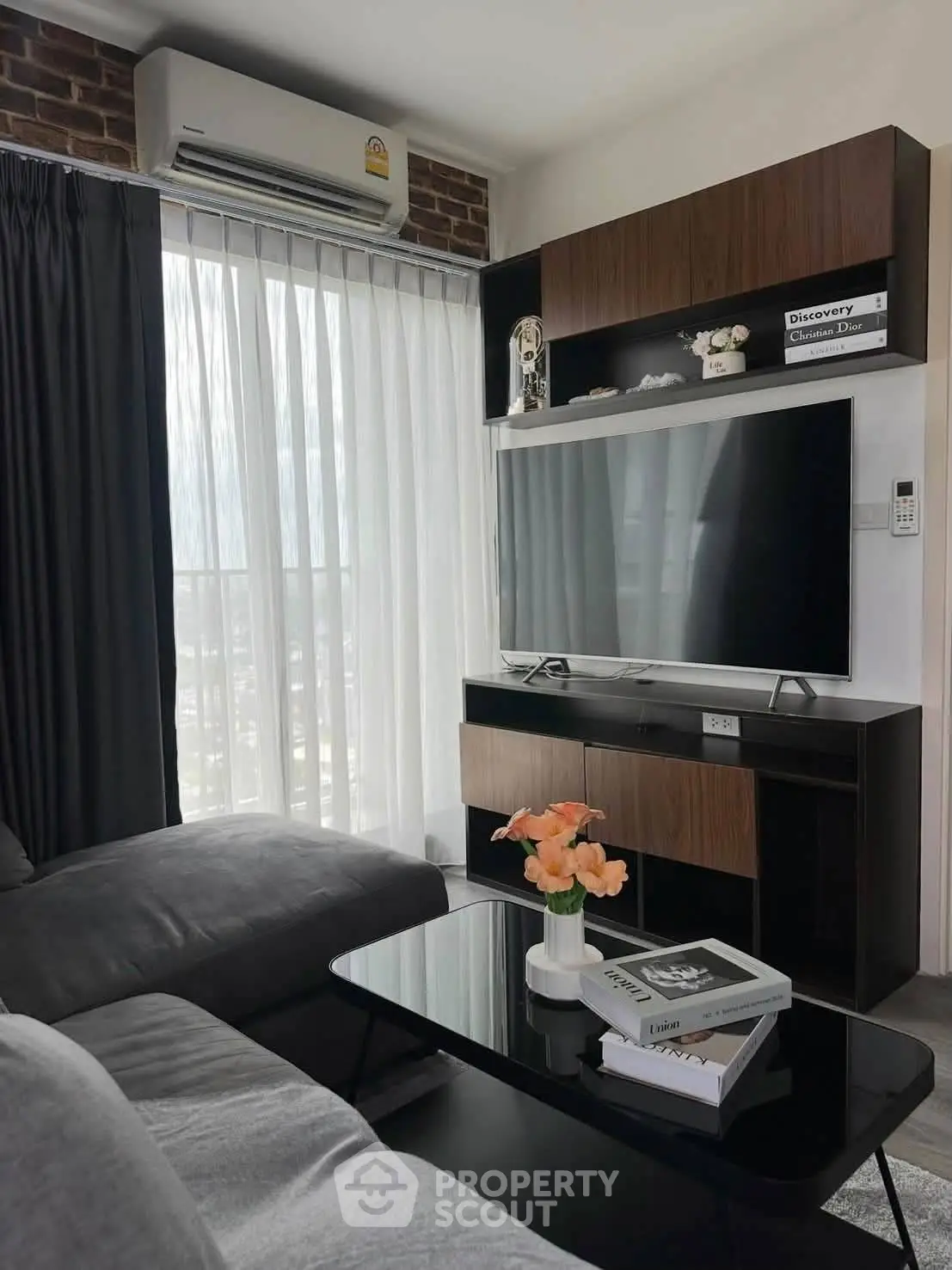 Modern living room with sleek furniture and large TV, featuring a cozy ambiance and natural light.