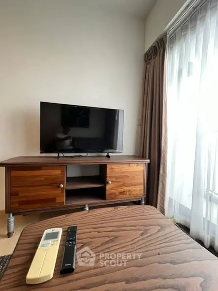 Cozy living room with wooden TV stand and large window for natural light.