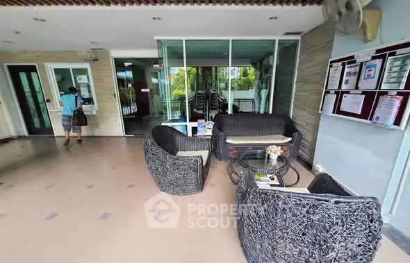 Chic apartment entrance with stylish outdoor seating and modern glass doors.