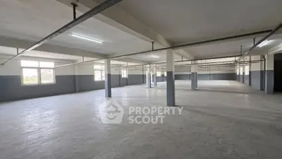 Spacious industrial-style open space with large windows and concrete flooring, ideal for versatile use.