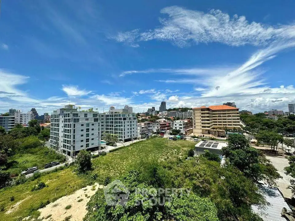 Stunning cityscape view showcasing modern buildings and lush greenery under a vibrant blue sky.