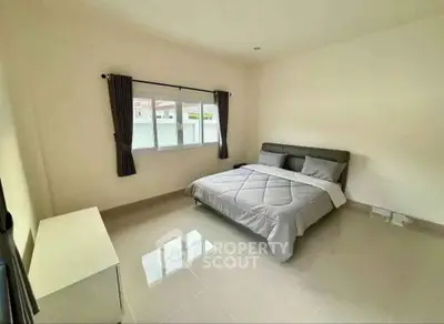 Spacious bedroom with modern decor and large window for natural light.