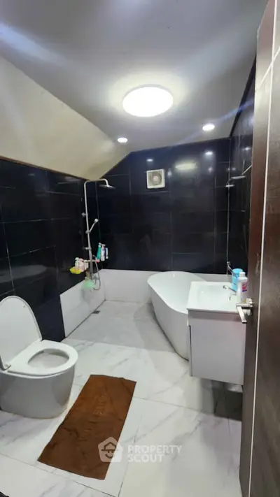 Luxurious modern bathroom with sleek black tiles and elegant bathtub