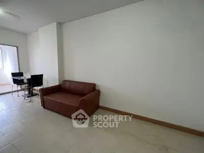 Spacious living room with modern sofa and dining area, perfect for comfortable living.