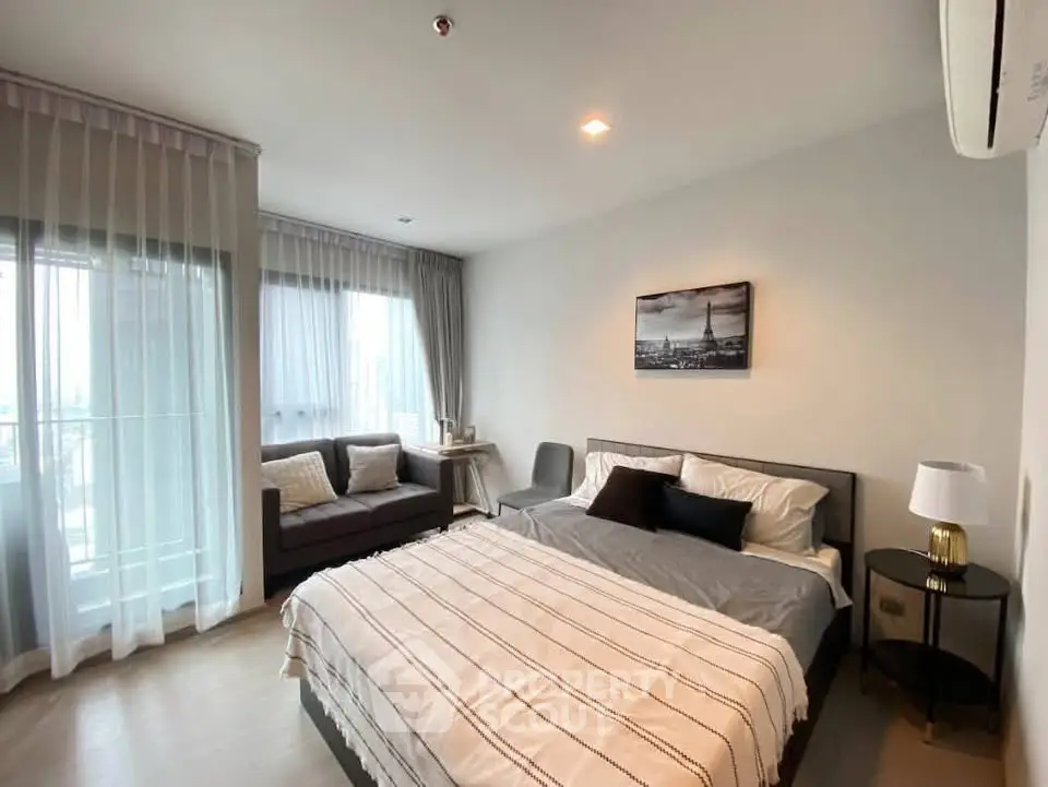 Modern bedroom with cozy decor and large windows offering natural light.