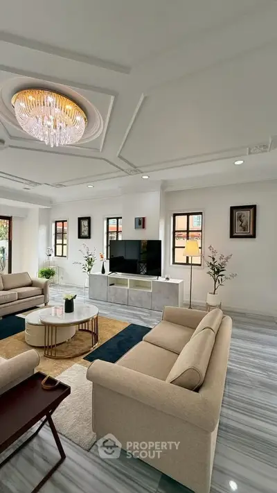 Luxurious living room with elegant chandelier and modern decor, featuring plush sofas and a sleek entertainment center.