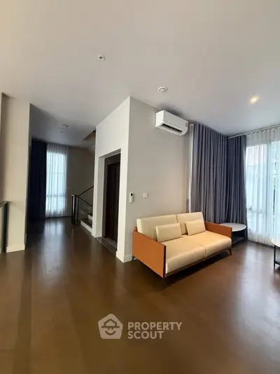 Spacious modern living room with sleek wooden flooring and elegant curtains