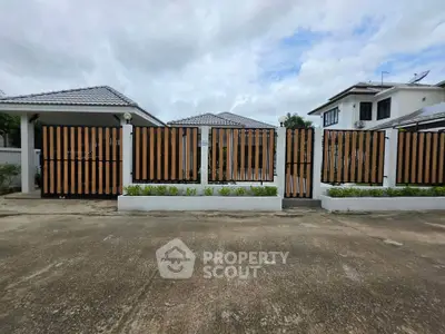 Charming suburban home with modern fence and lush greenery, perfect for family living.