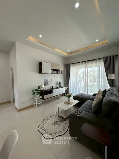 Modern living room with sleek furniture and large windows offering natural light.