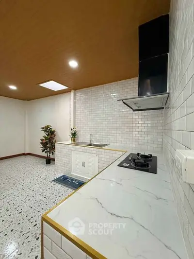 Modern kitchen with sleek marble countertops and gas stove in a stylish open layout.