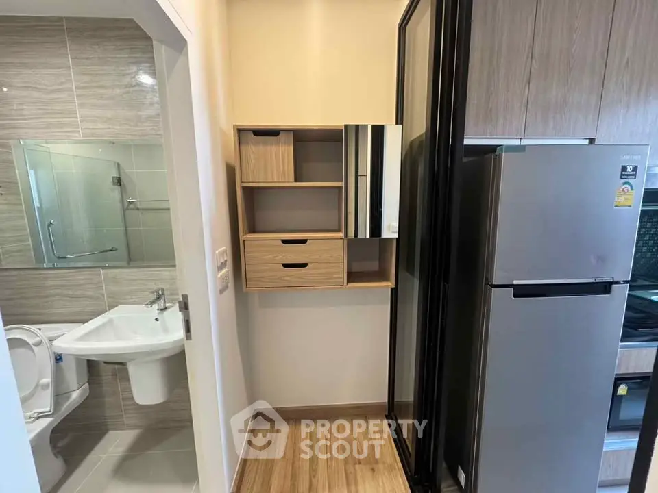 Compact apartment interior with modern bathroom and kitchen featuring sleek appliances and wooden flooring.