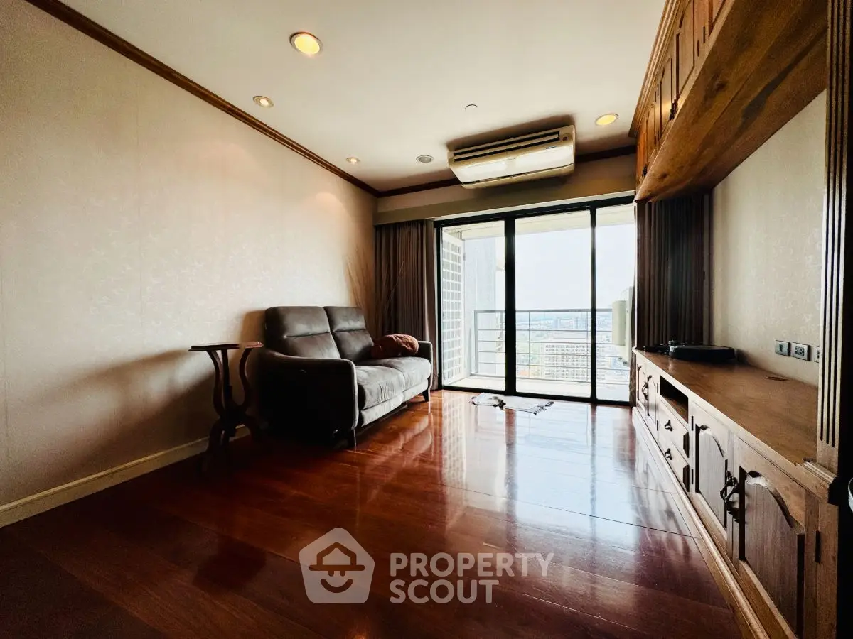 Spacious living room with wooden flooring and balcony view in modern apartment