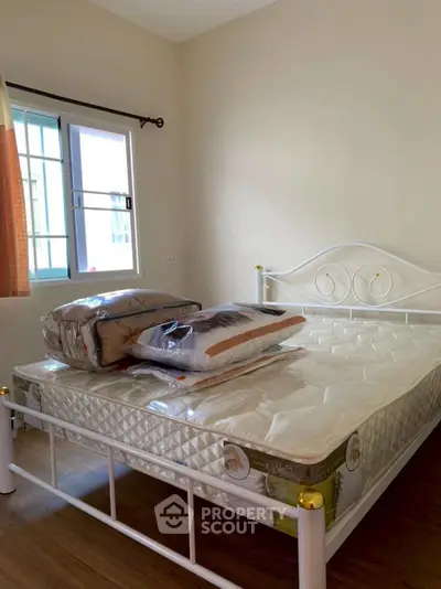 Cozy bedroom with a metal bed frame and natural light from the window.