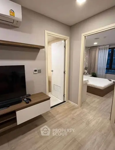 Modern apartment interior with cozy bedroom and stylish living area featuring TV and air conditioning.