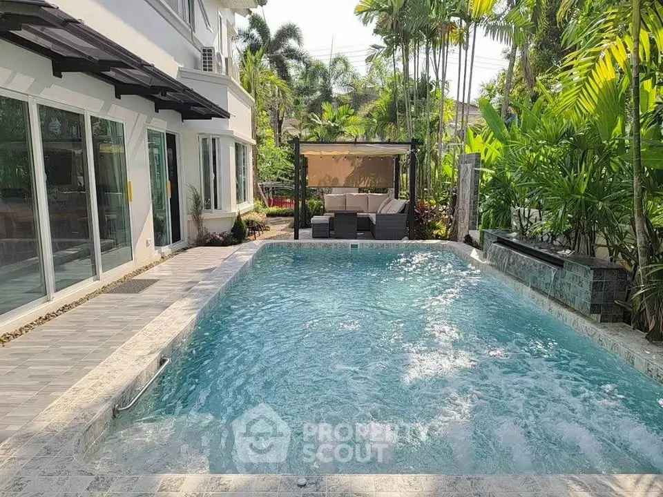 Luxurious outdoor pool area with lush greenery and modern seating, perfect for relaxation and entertainment.