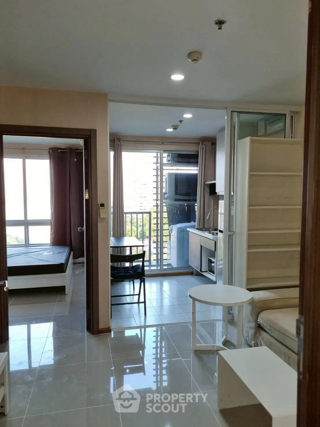 Modern apartment interior with open layout, featuring a cozy living area, dining space, and bedroom view.