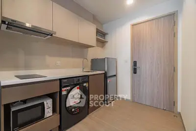 Modern kitchen with sleek appliances and compact design, featuring washing machine and microwave for convenience.