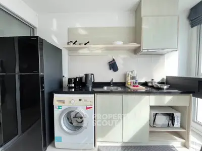 Modern kitchen with sleek appliances including washing machine and microwave, featuring ample storage and natural light.