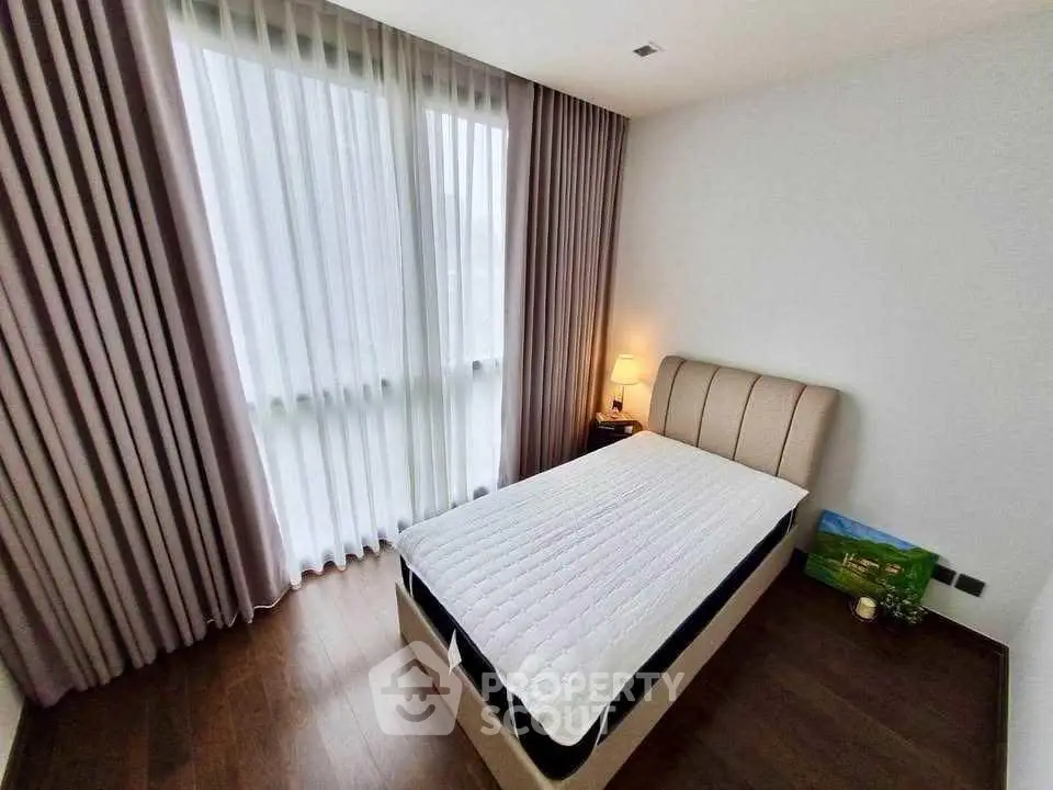 Cozy bedroom with elegant curtains and soft lighting, perfect for relaxation.