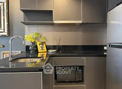 Modern kitchen with sleek cabinetry, built-in microwave, and elegant black countertops.