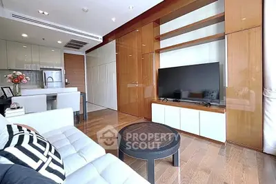 Modern living room with sleek design, featuring a large TV, stylish furniture, and open kitchen layout.