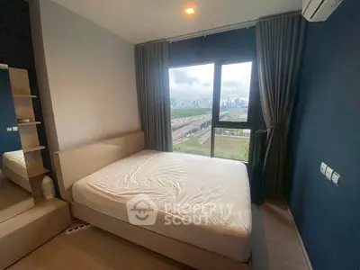 Modern bedroom with large window offering stunning city view, featuring minimalist design and cozy ambiance.