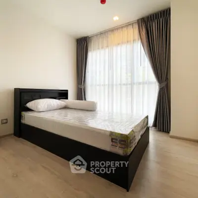 Modern bedroom with large window and elegant curtains, featuring a sleek bed frame and natural light.