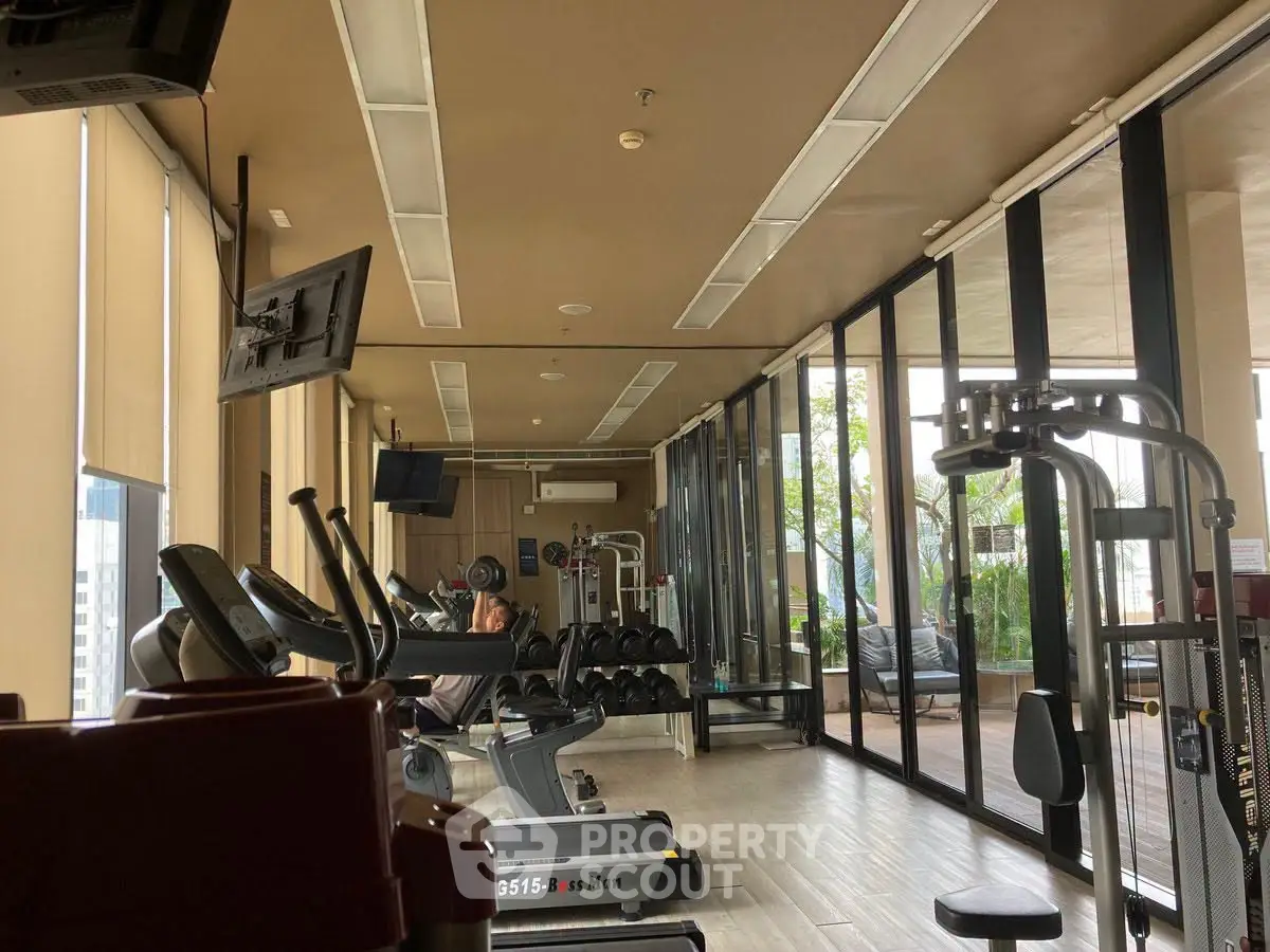 Spacious gym with modern equipment and large windows offering a scenic view, perfect for fitness enthusiasts.
