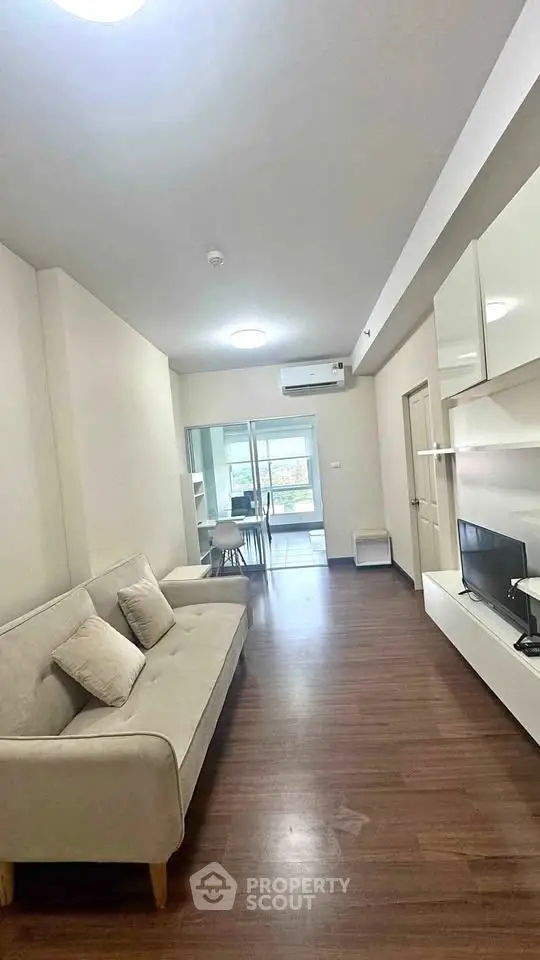 Modern living room with sleek furniture and open layout, featuring a cozy sofa and flat-screen TV.
