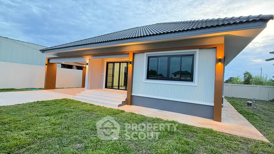 Modern single-story house with spacious lawn and elegant exterior lighting.
